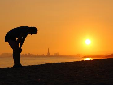 Horizon, person on beach bending over in heat