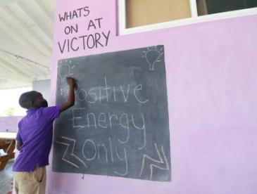 A student writes Positive Energy Only on a chalkboard 