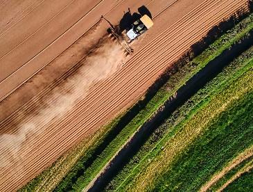 Aerial view of tractor rolling across a farm field