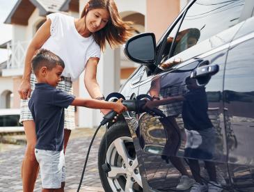 Caregiver and child charging an electric vehicle.