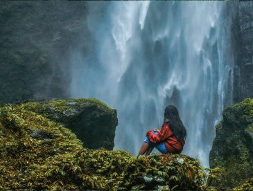 Girl on rock looking at waterfall