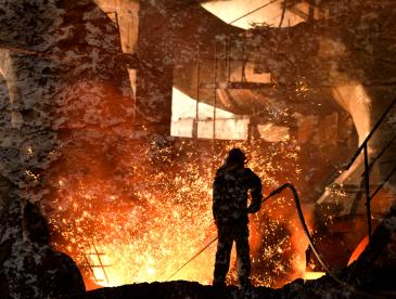 Steelworker working with very hot materials, amidst sparks.