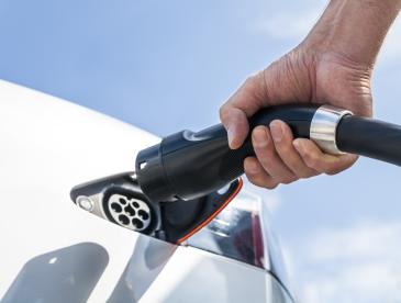 Close view of a hand plugging in an electric vehicle