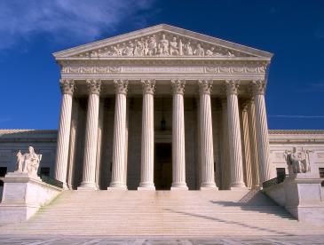 Supreme Court building, with majestic columns, under a blue sky.
