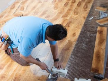 Man installing floor panels in a house