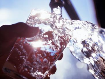 Tap water flowing into a drinking glass.