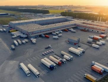 Warehouse with trucks in parking lot.