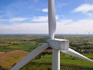 A giant wind turbine with many smaller ones in the distance across farming fields
