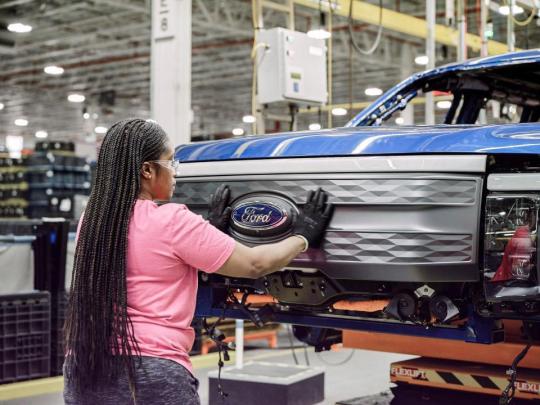 A Ford assembly worker putting a grill onto an electric Ford truck