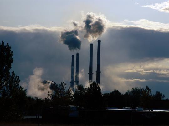 Smokestacks in the distance, releasing clouds of emissions.