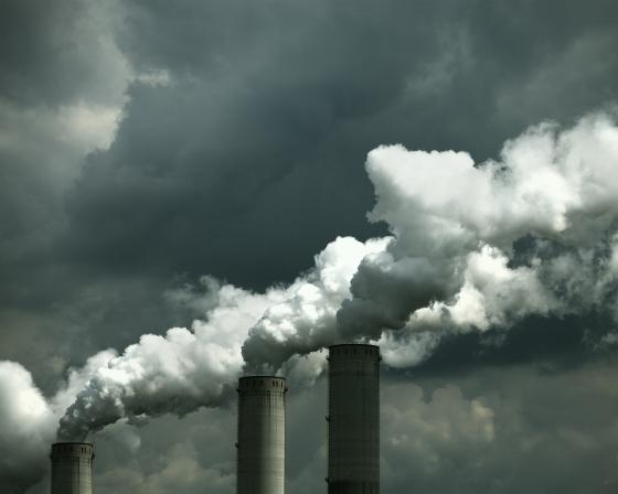 Smokestacks releasing emissions on a cloudy day.