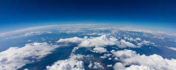 Curvature of planet earth. Aerial shot. Blue sky and clouds over land.