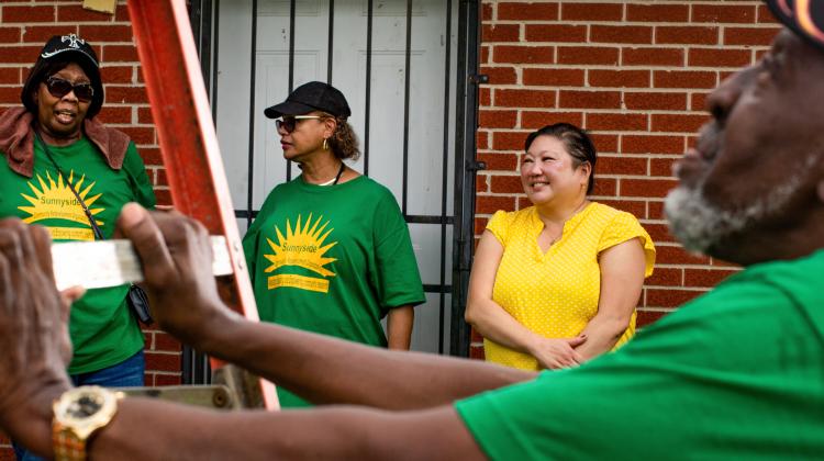 A group of Sunnyside Community Redevelopment Organization members standing in front of a home.